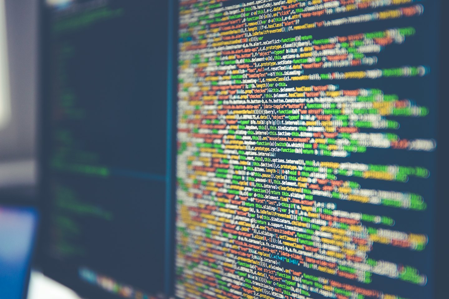 Código de programación colorido en la pantalla oscura de un monitor de computadora.